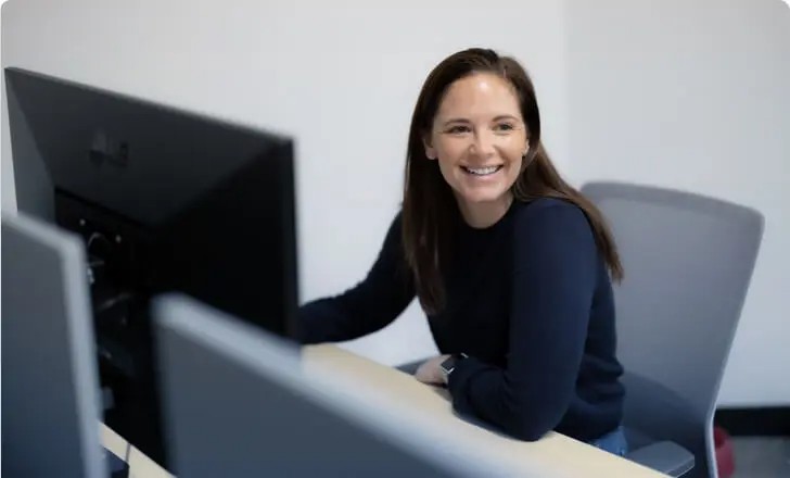 A women laughing while working on computer