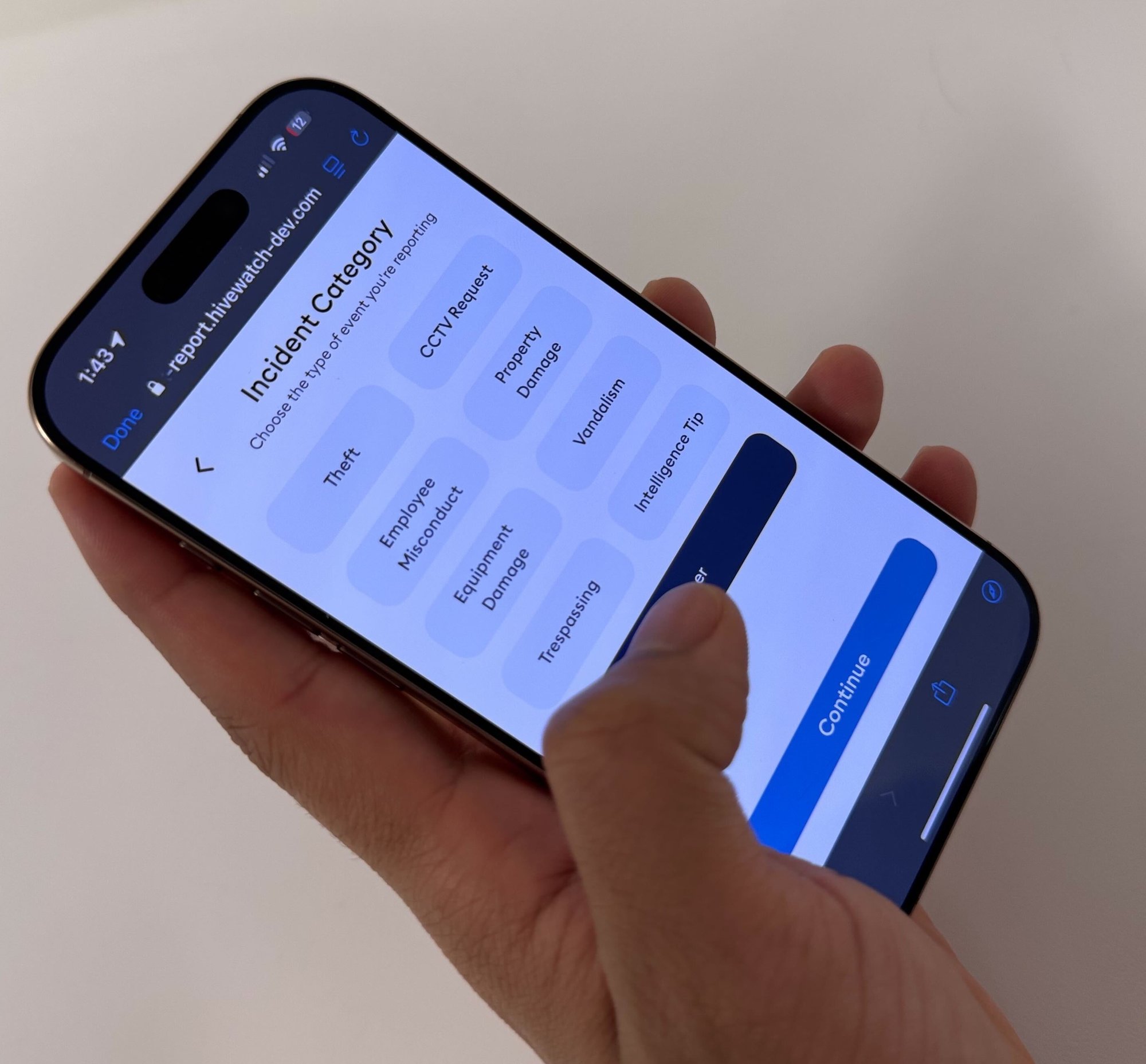 Hand holding mobile device with list of incident categories on the screen