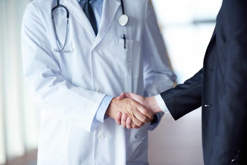 doctor handshake with a patient at doctor's bright modern office in the hospital